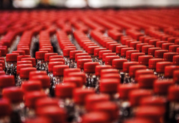 Soft drinks bottled lined up in rows with red lids