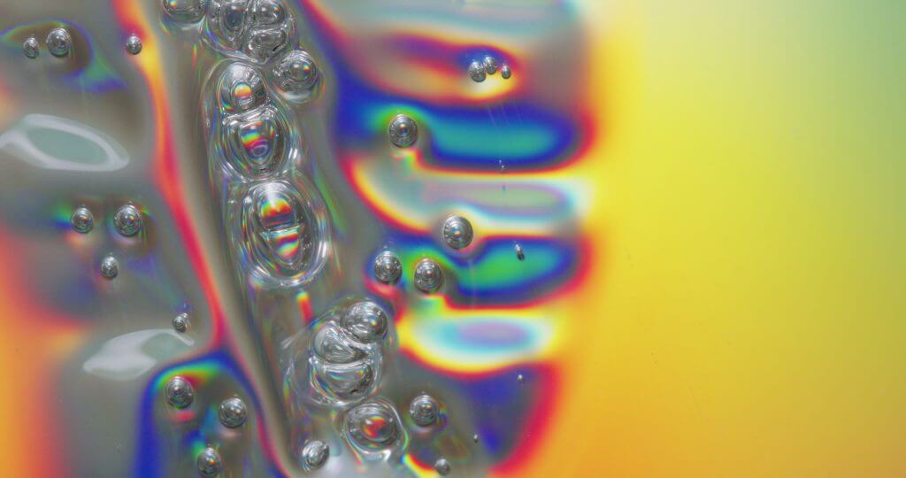 macro image of clear plastic being melted, producing silver and rainbow coloured bubbles