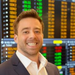 One of our Traders smiling in front of a trading screen.