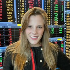 An office worker standing in front of a trading screen