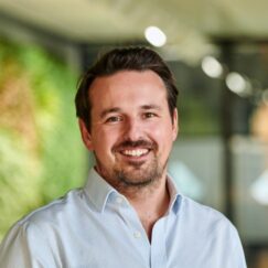 Smiling team member in front of a green wall
